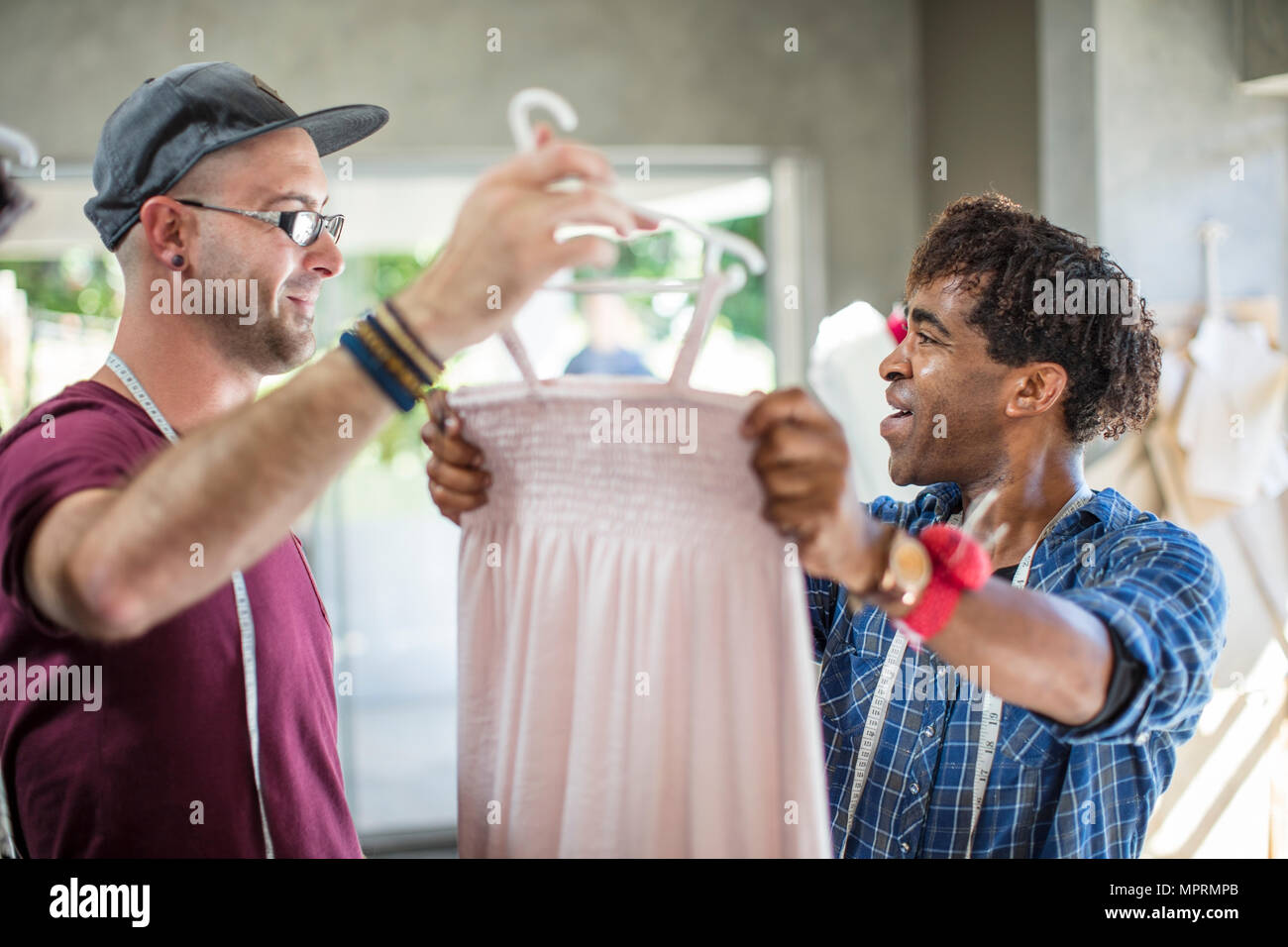 Smiling fashion designer showing dress to colleague Stock Photo