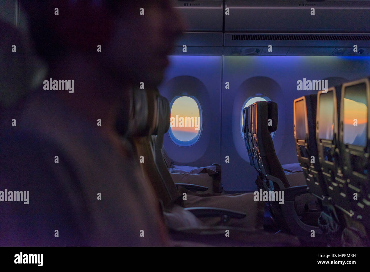Young man in plane wearing headphones Stock Photo Alamy