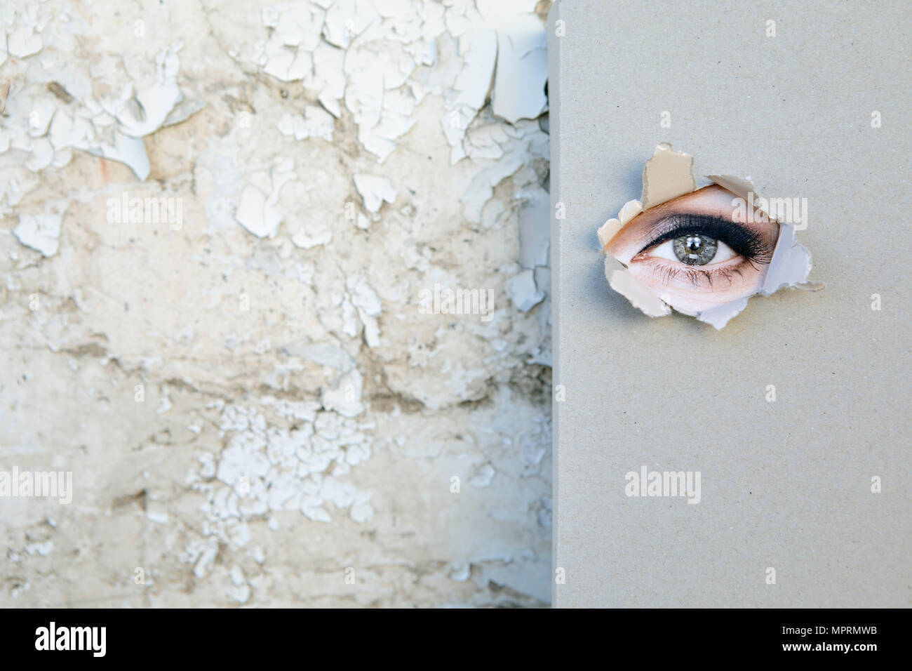 Book with eye looking through the cover  leaning against weathered wall Stock Photo