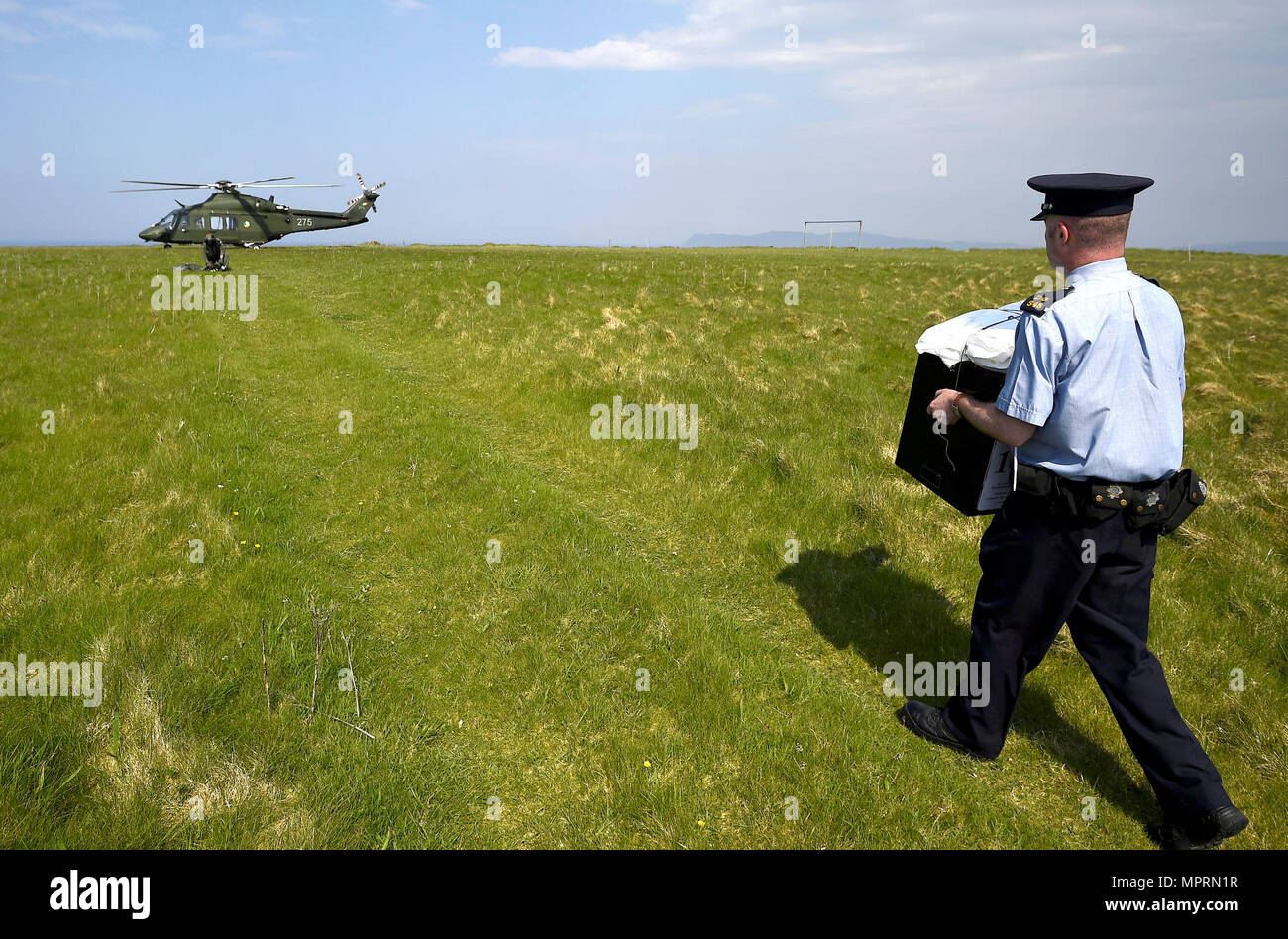 Garda Alan Gallagher carries a polling box, used, a day early, by the few people that live off the coast of Donegal on the island of Inishbofin, to vote in the referendum on liberalising abortion law, in Inishbofin, Ireland. Stock Photo