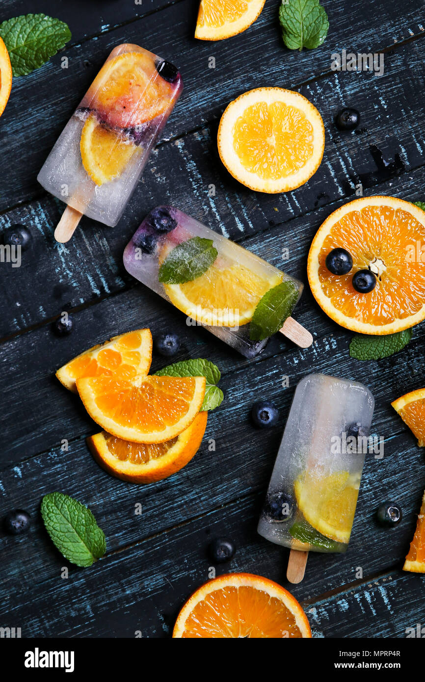 Homemade detox popsicles with blueberries, orange slices and mint leaves on black wood Stock Photo