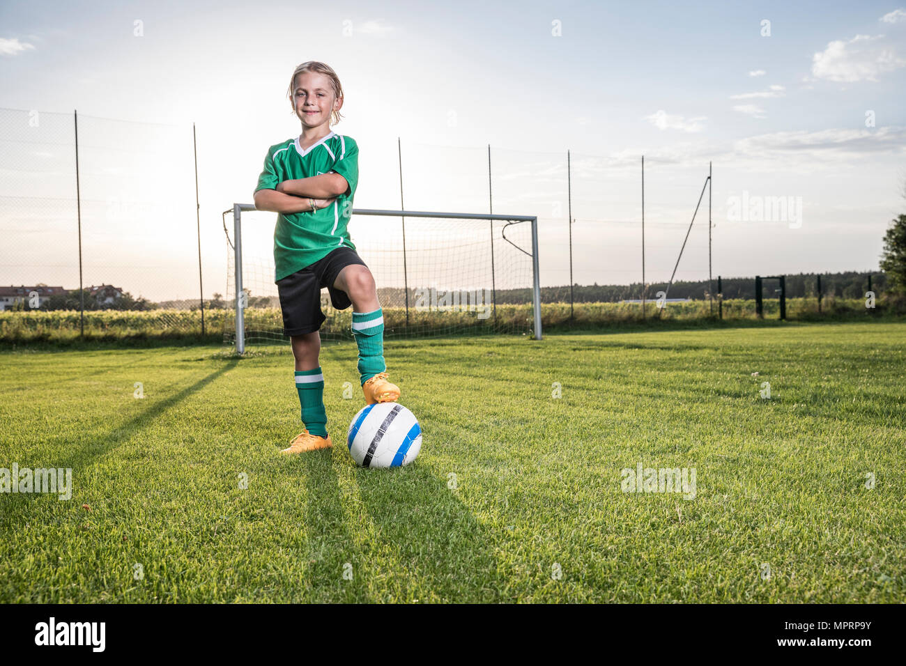 Portrait of confident young football player with ball on football ground Stock Photo