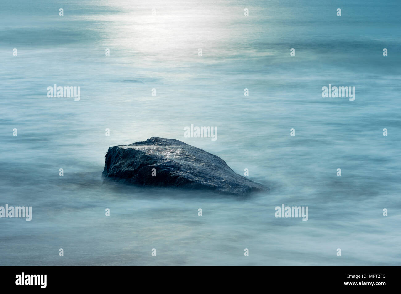 Boulder  with moving ocean water. Stock Photo