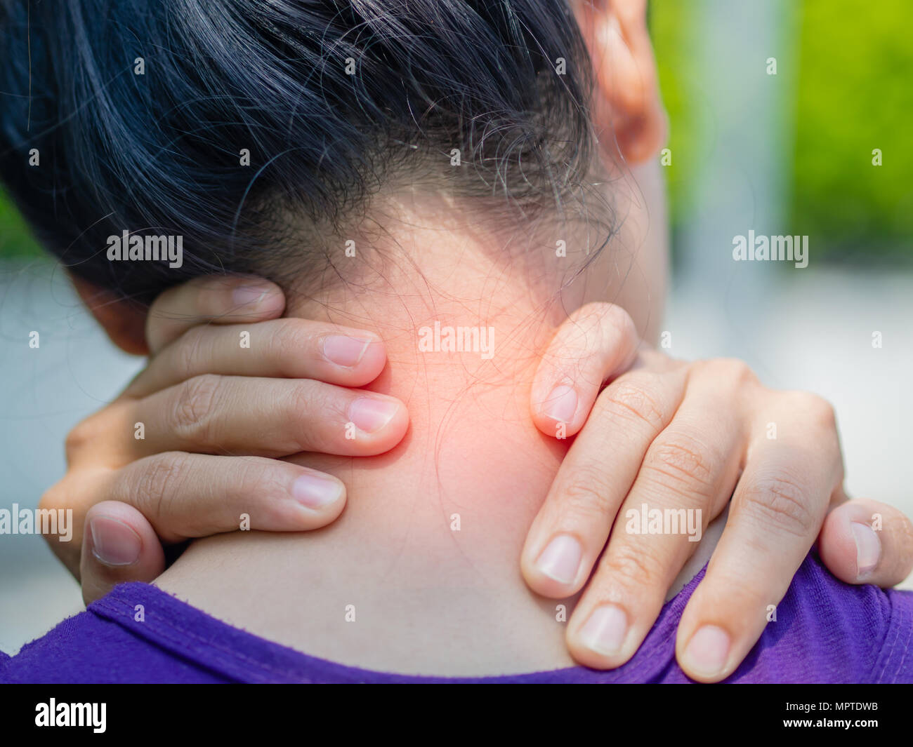 Athletic young woman touching her neck by painful injury, over a nature