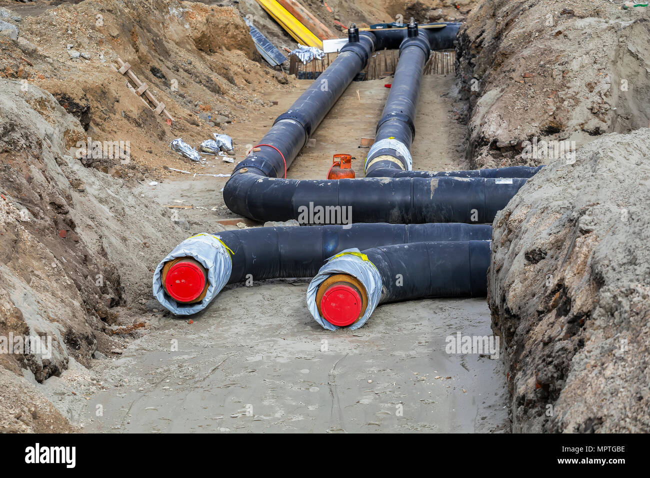Installing district heating pipes in a trench, laying insulated pipe