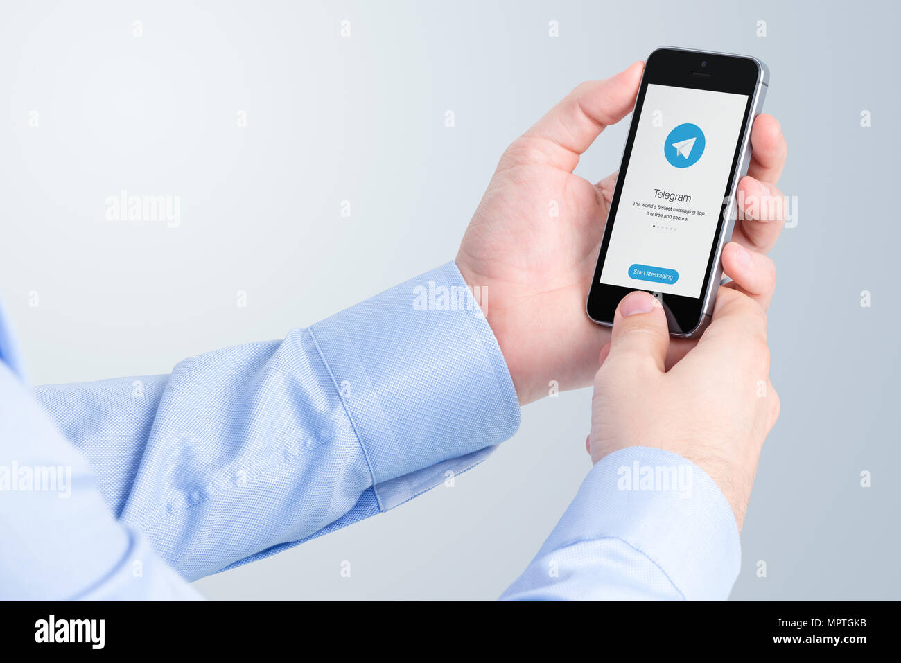 Telegram messenger on iPhone display in male hands. Stock Photo