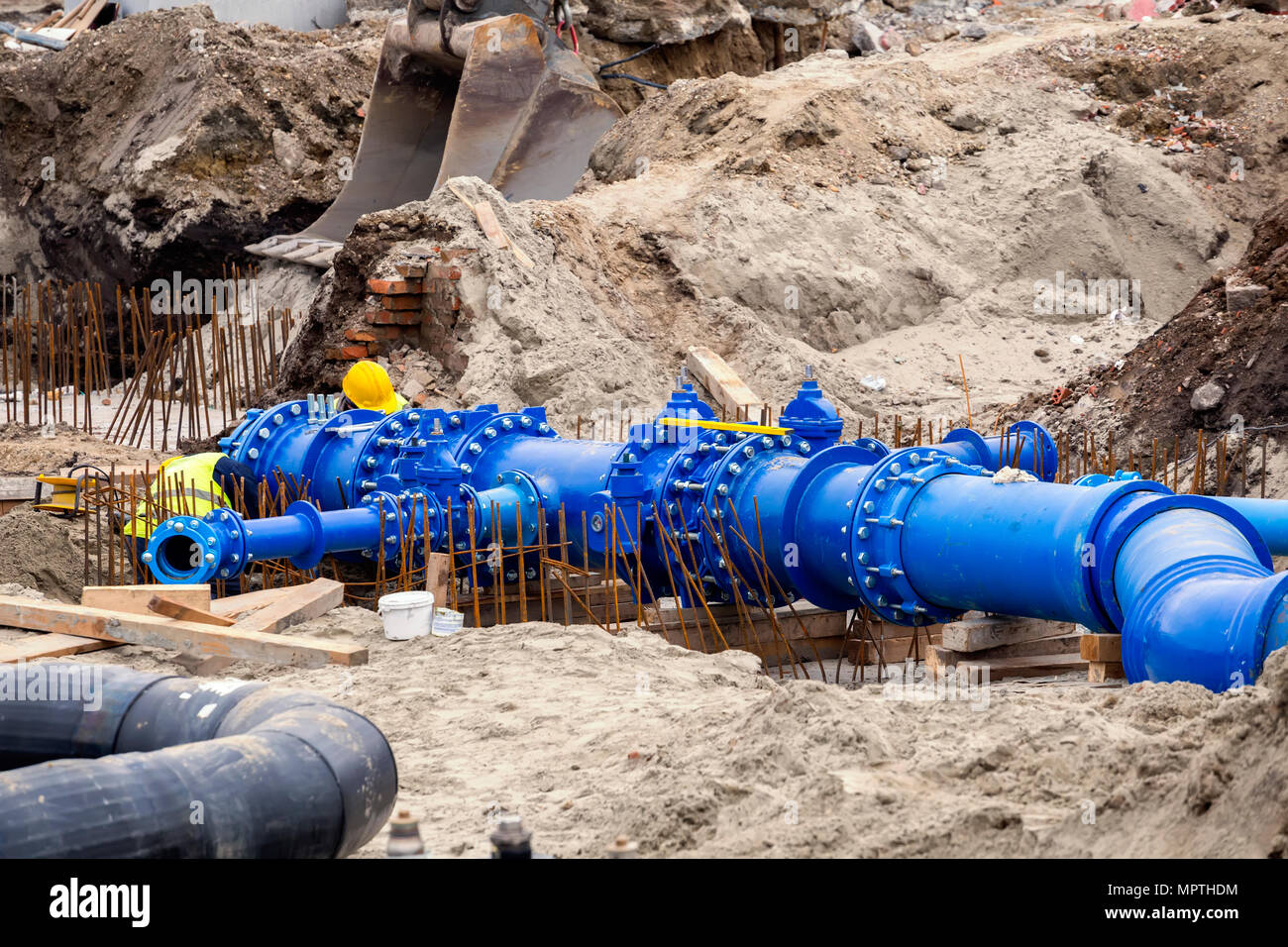 Workers laid water system pipeline at construction site. City construction of water supply pipeline with gate valves. Construction of drinking water p Stock Photo