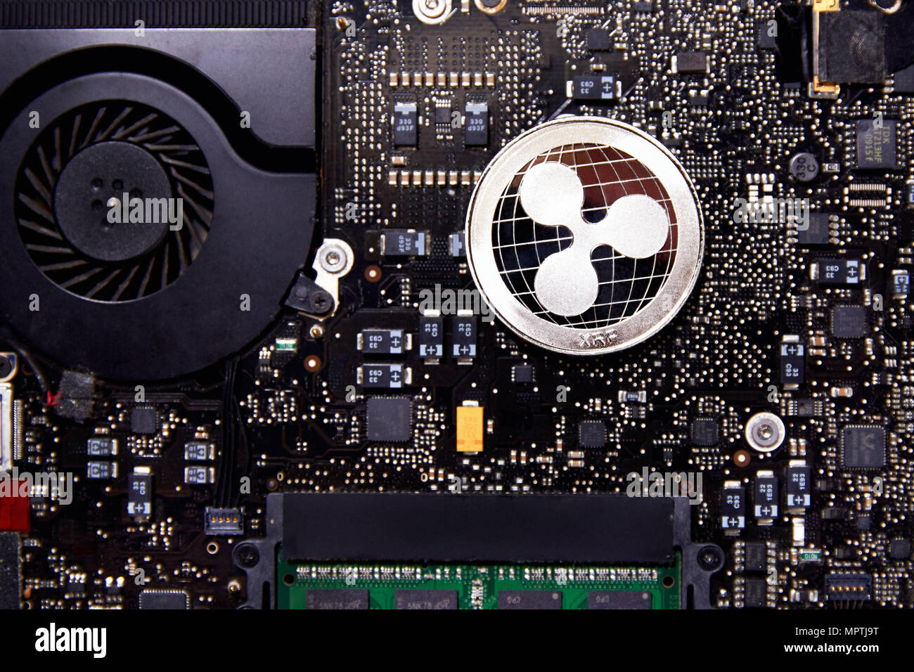 A Ripple physical coin sitting on a computer motherboard with a fan and RAM. real-time gross settlement system, exchange and remittance network Stock Photo