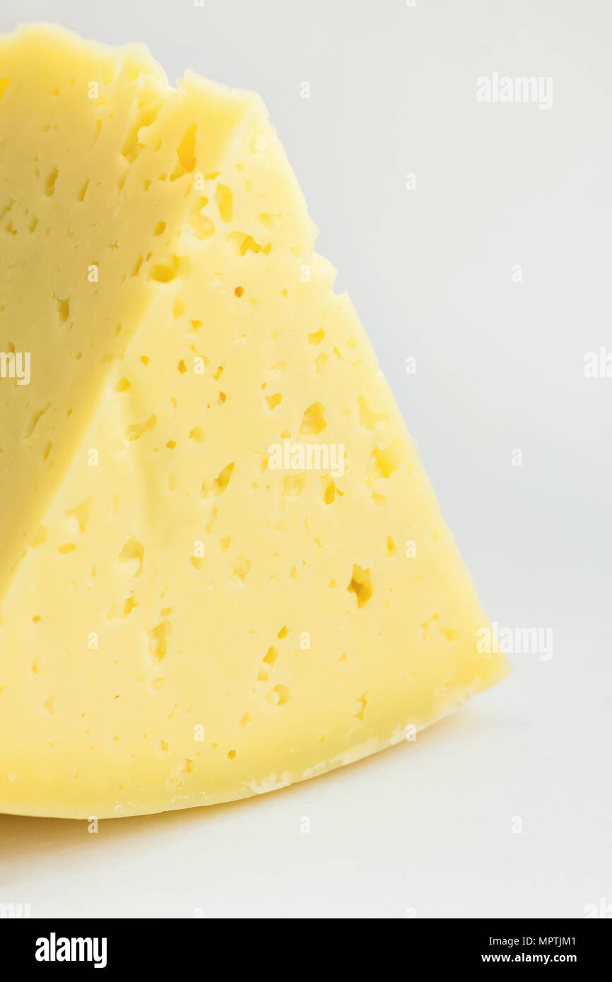 Big Chunk Wedge of Alpine Creamy Appetizing Light Yellow Tilsit Cheese on White Background. Texture with Cracks and Holes. Minimalist Style. Poster Ba Stock Photo