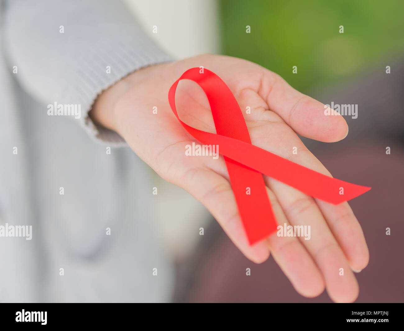 Closeup woman hand holding red ribbon HIV, world AIDS day awareness ...
