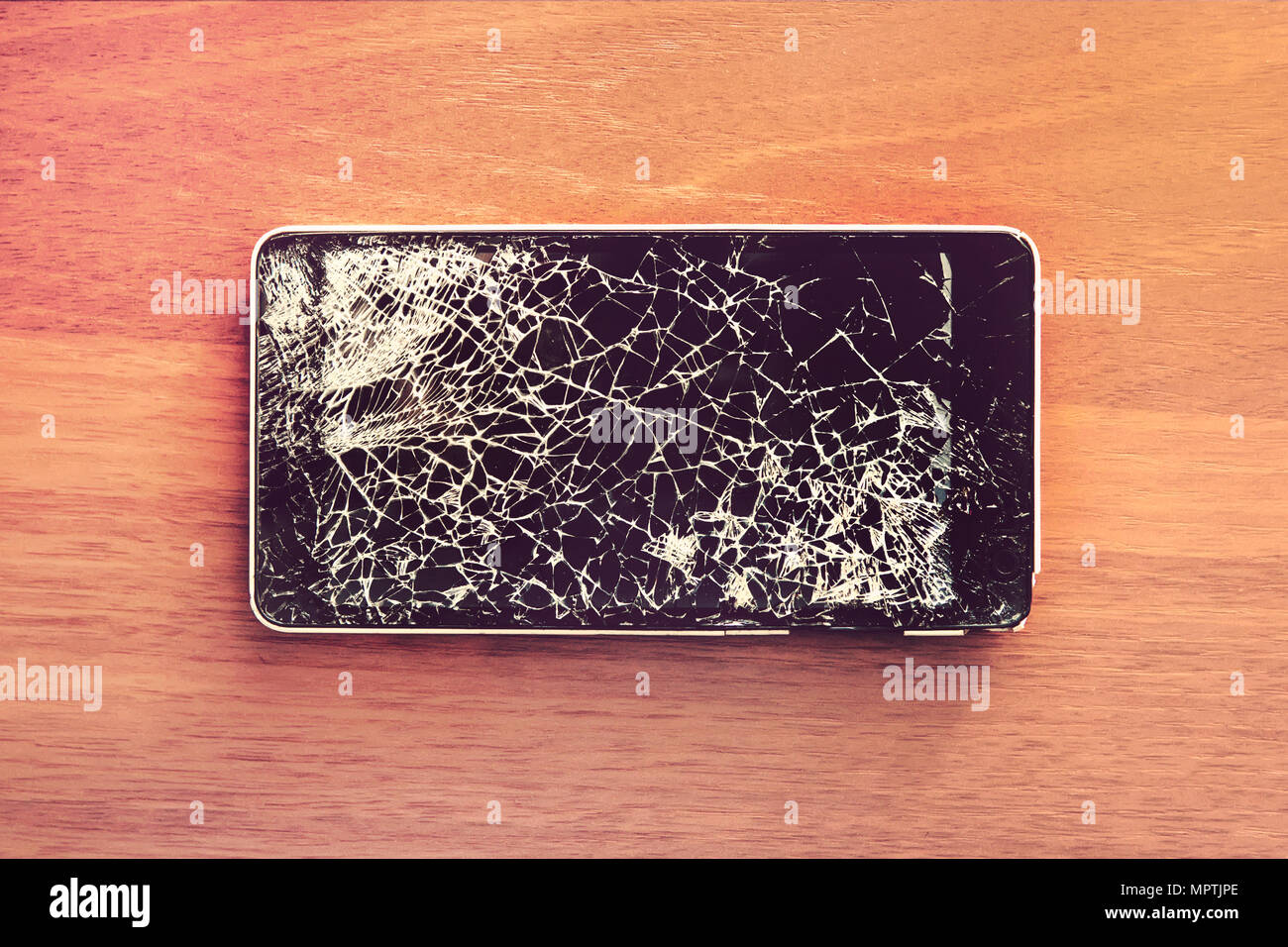 Smartphone mobile with a broken screen. Background wood Stock Photo