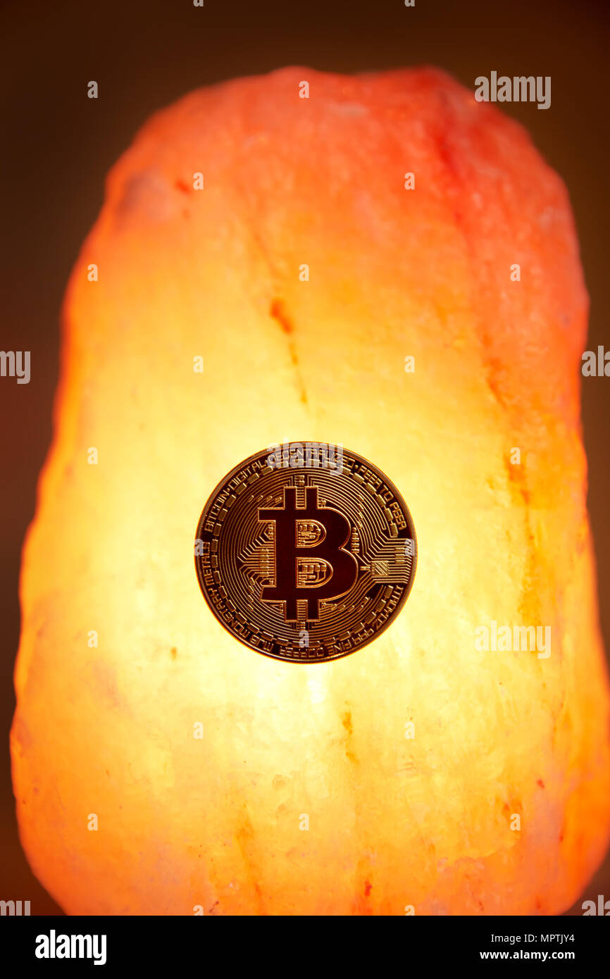 A physical gold Bitcoin with the public domain logo sits on a Himalayan sea  salt crystal with a glowing warm light radiating Stock Photo - Alamy