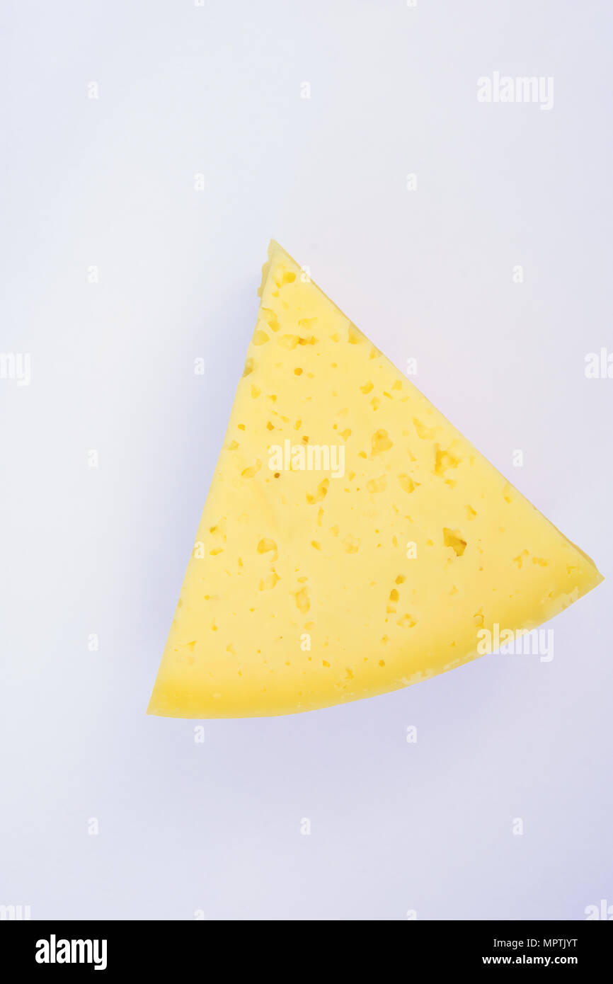 Triangular Chunk Wedge of Alpine Creamy Appetizing Light Yellow Tilsit Cheese on White Background. Texture with Cracks and Holes. Minimalist Style. Po Stock Photo
