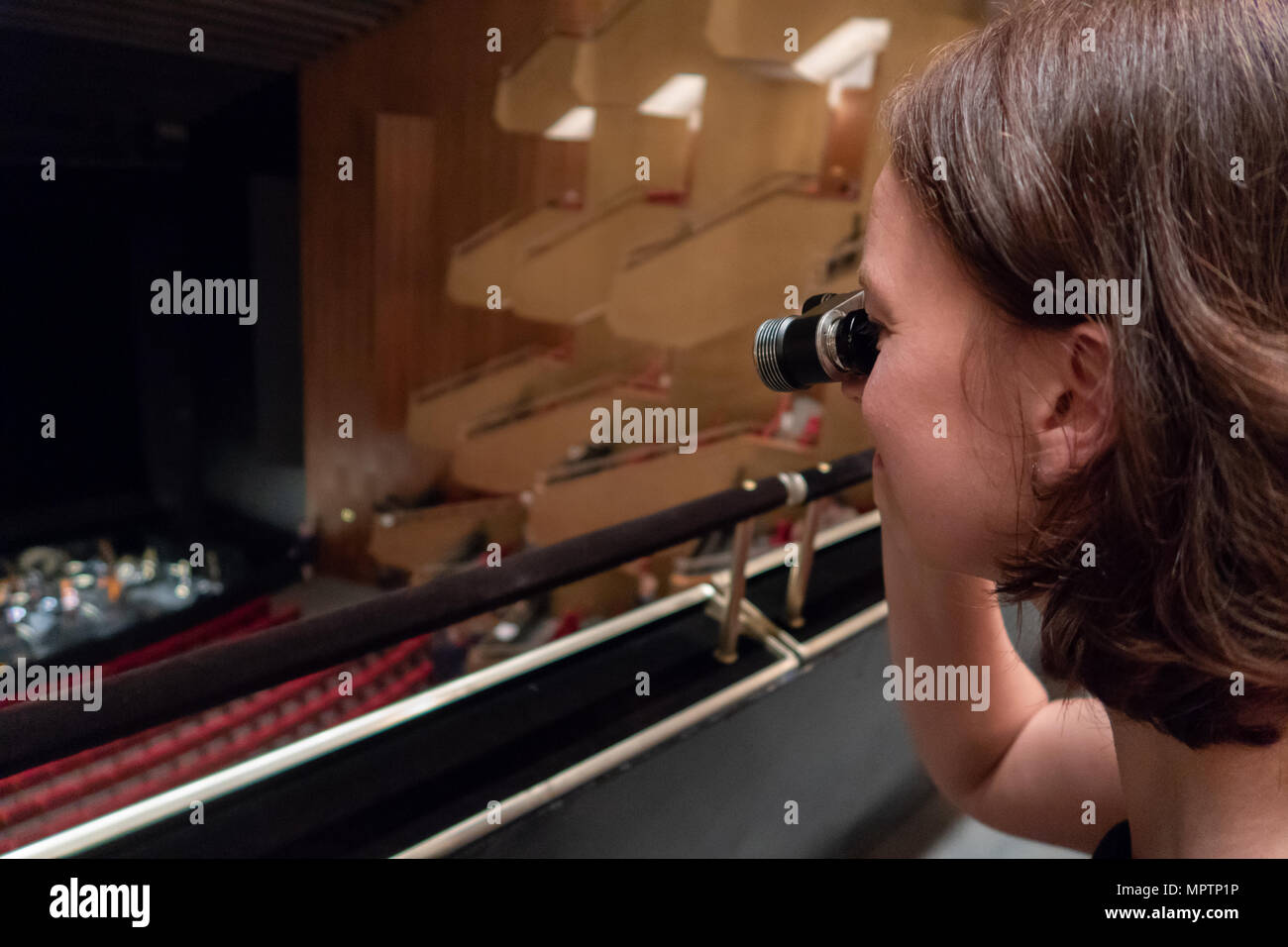 A woman is watching the orchestra in a theatre with opera glasses Stock Photo