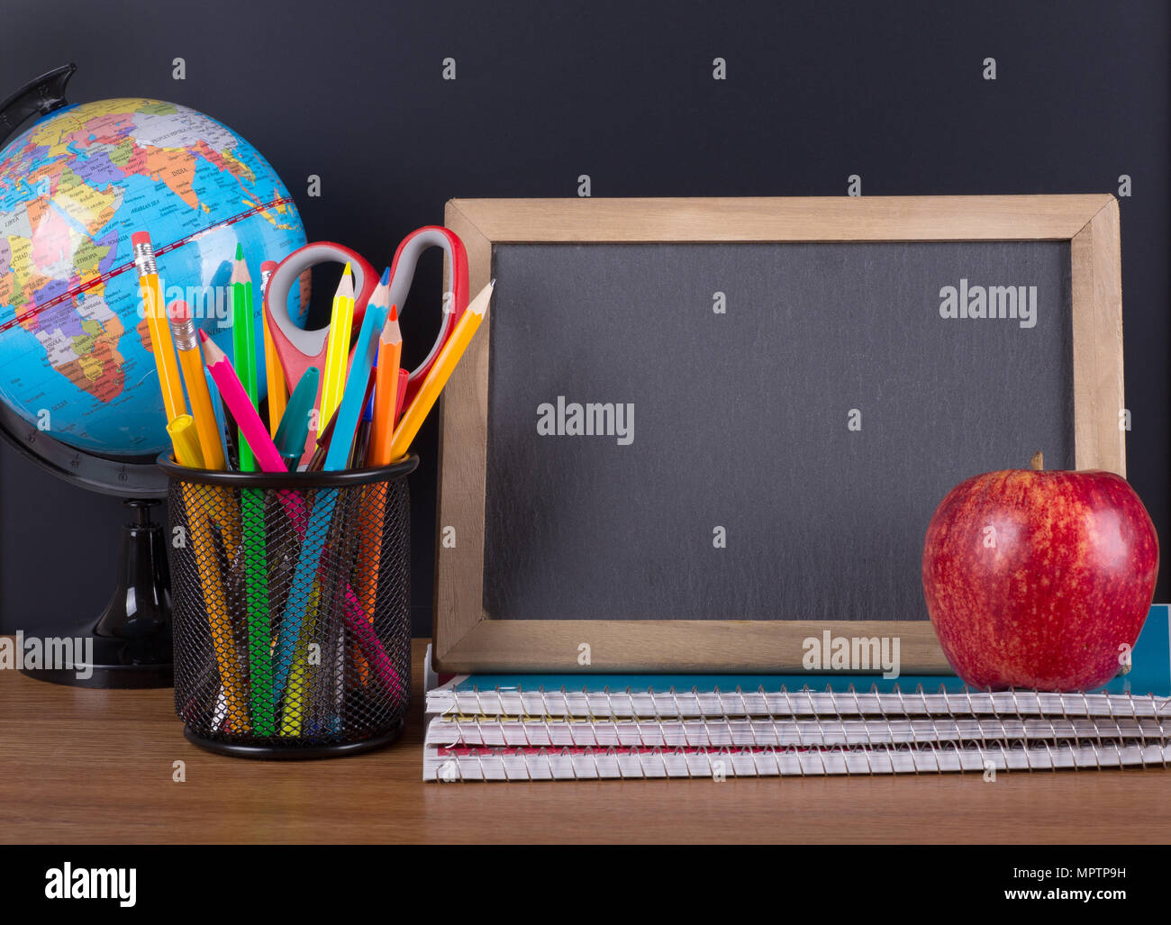 School accessories on a wooden desktop with a blank chalkboard for copy space Stock Photo