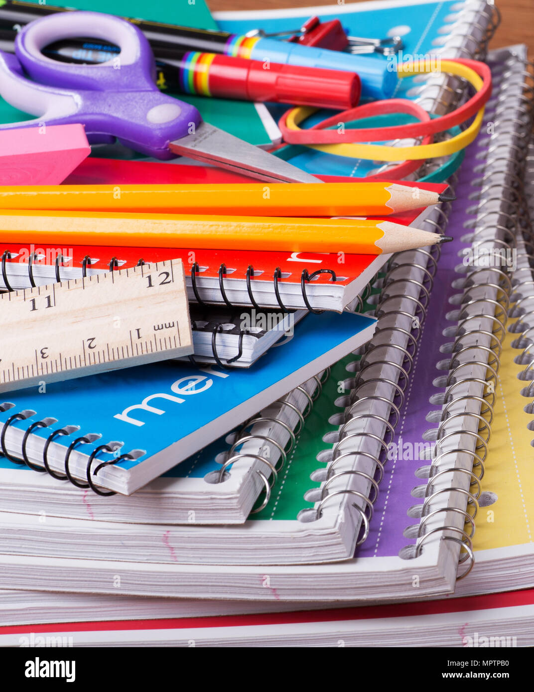 Closeup of an assortment of school supplies on top of a stack of spiral notebooks Stock Photo