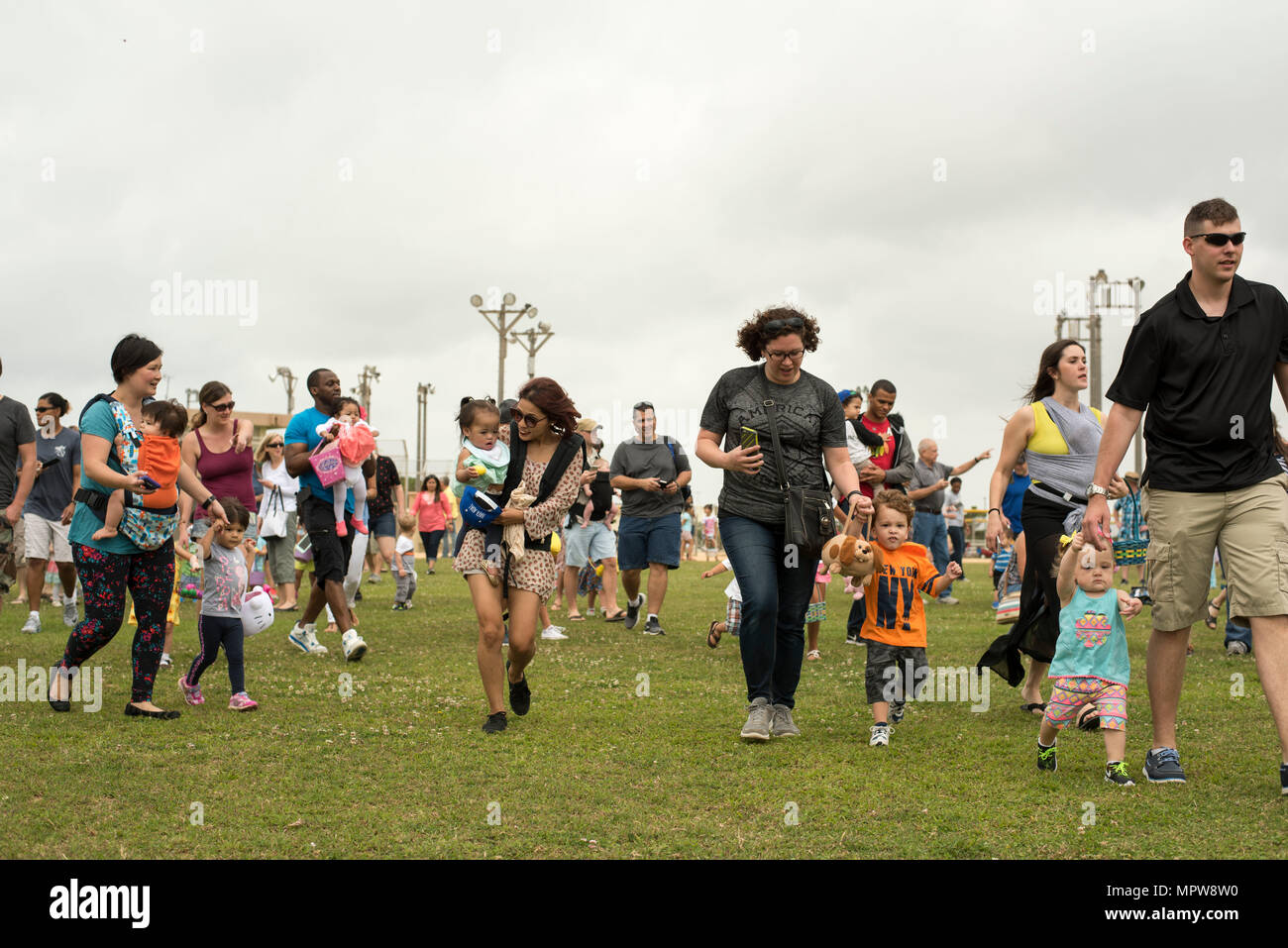 Families race to collect Easter eggs scattered on the Four Diamonds softball field April 15, 2017, at Kadena Air Base, Japan. The Eggsplosion, an annual event hosted by the 18th Force Support Squadron, featured egg hunts for different age groups and also hosted a “Kiddie Land” area with amusement rides designed for children. (U.S. Air Force photo by Senior Airman Omari Bernard/Released) Stock Photo