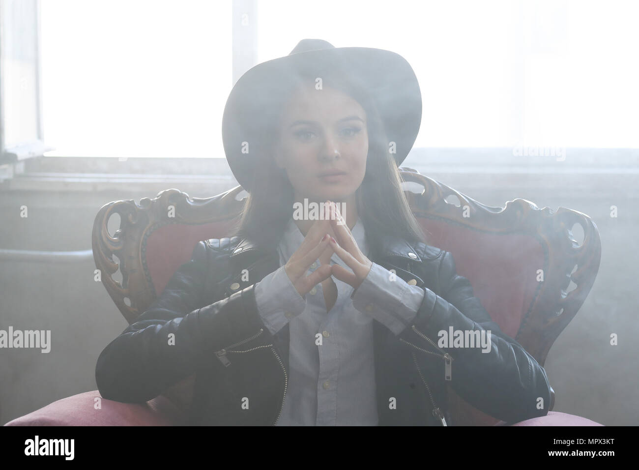 Woman In Room Full Of Smoke On A Red Armchair Stock Photo
