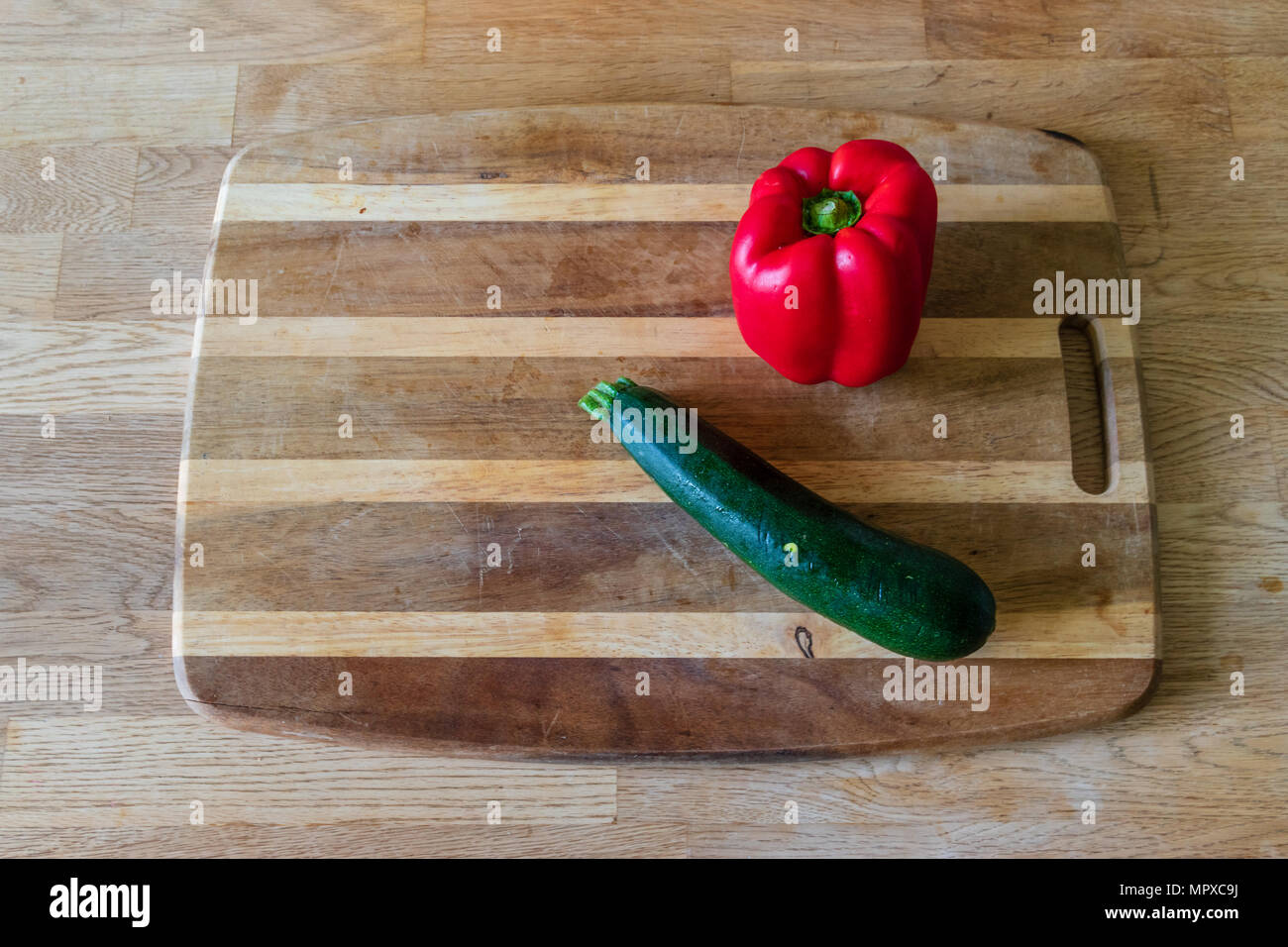 A red pepper and courgette on a chopping board Stock Photo