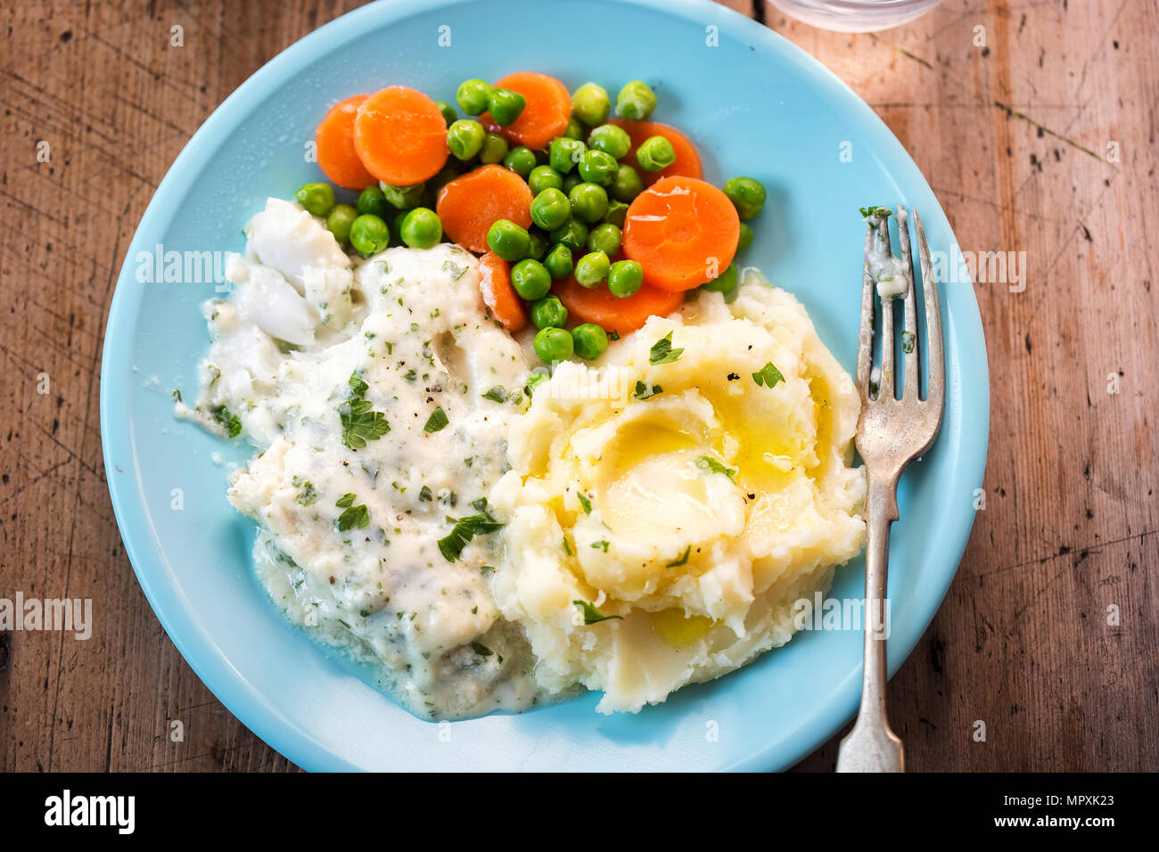 Cod fillet in parsley sauce with mash, peas and carrots Stock Photo - Alamy