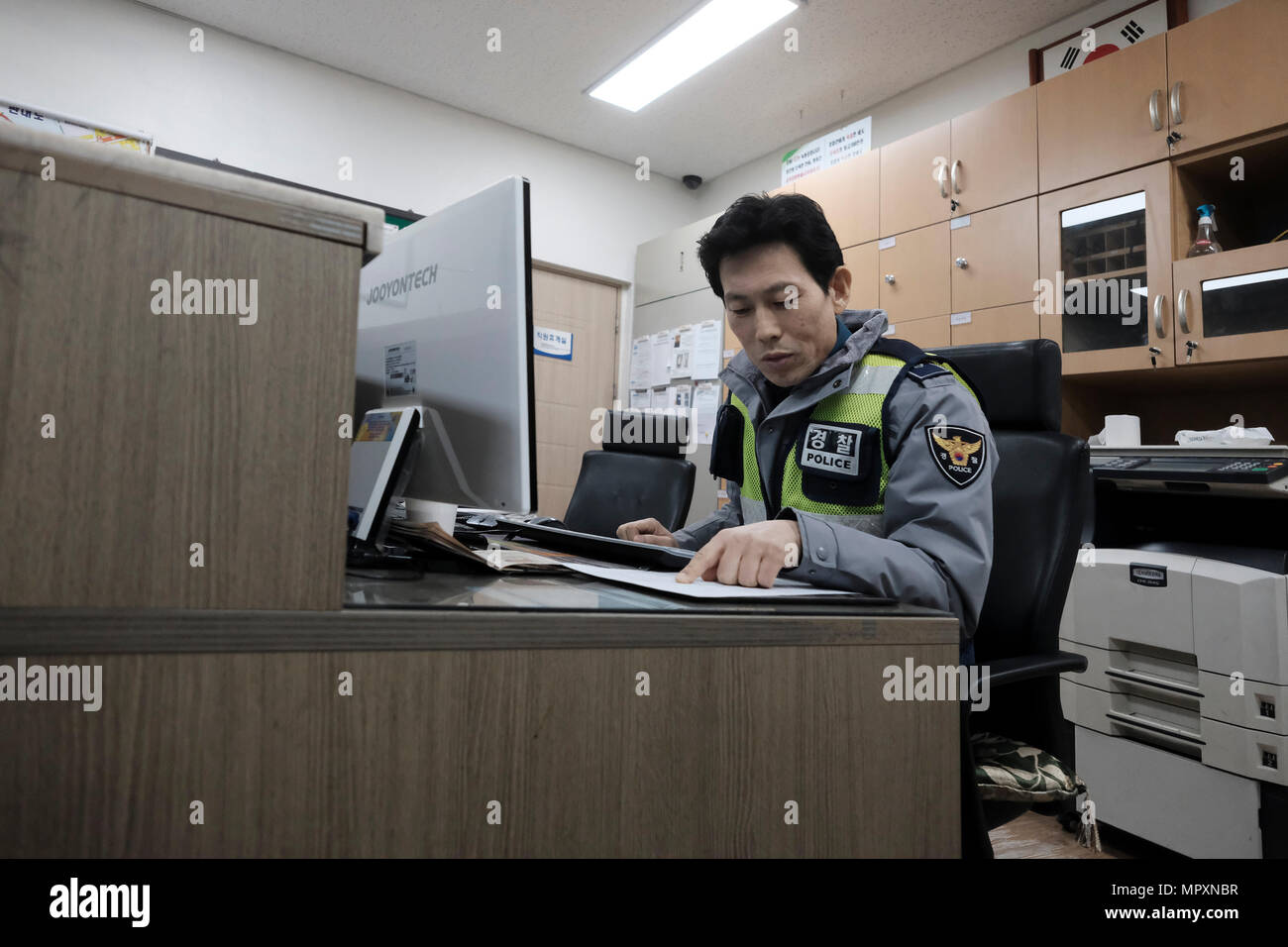 A South Korean policeman filling up a report in a police station in the city of Seoul capital of the Republic of Korea commonly known as South Korea. Stock Photo