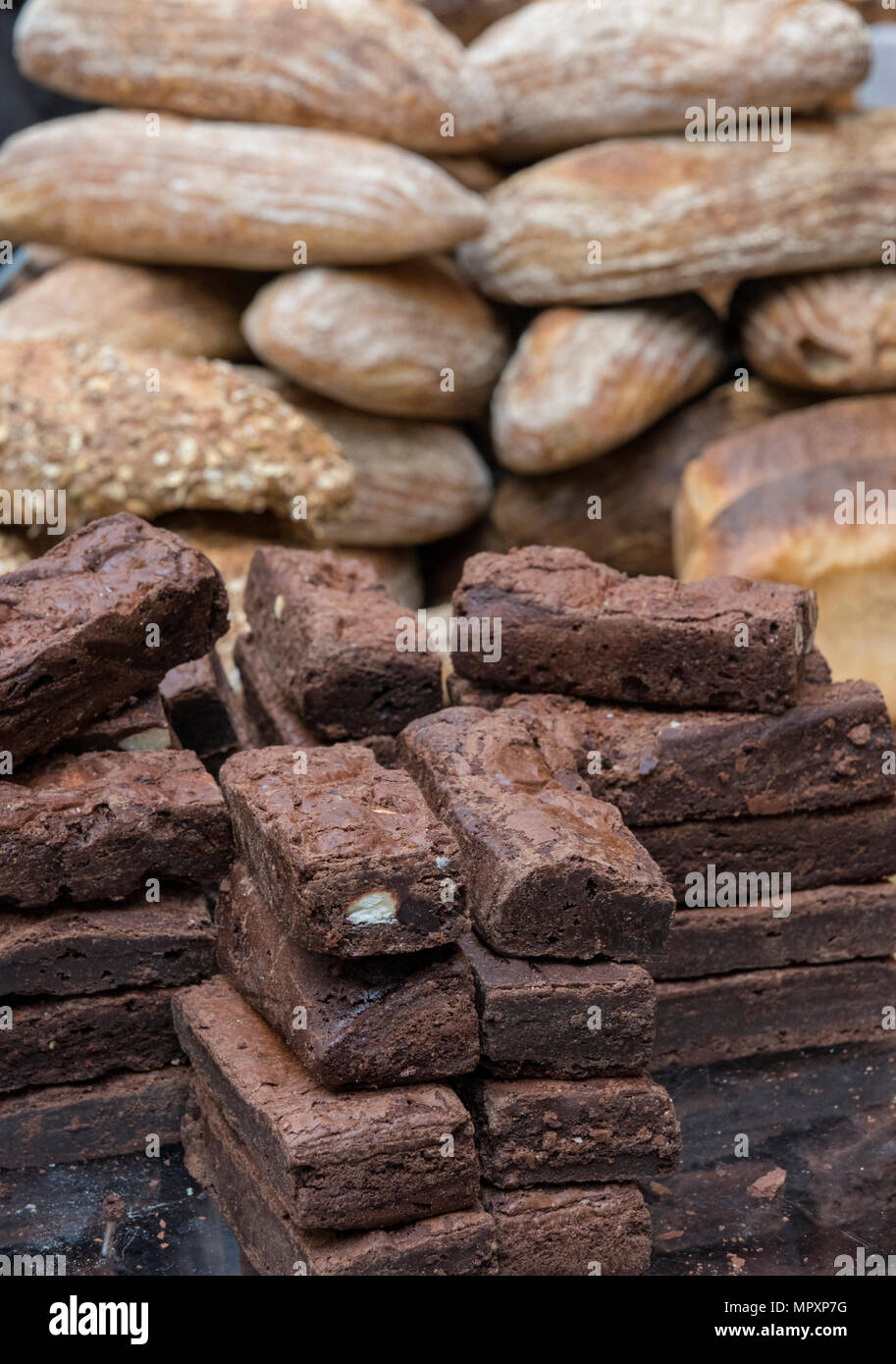 a pile of chocolate brownies and some other baked delicacies and breads at a bakers stall on borough market london. chocolate treats and baked cakes. Stock Photo