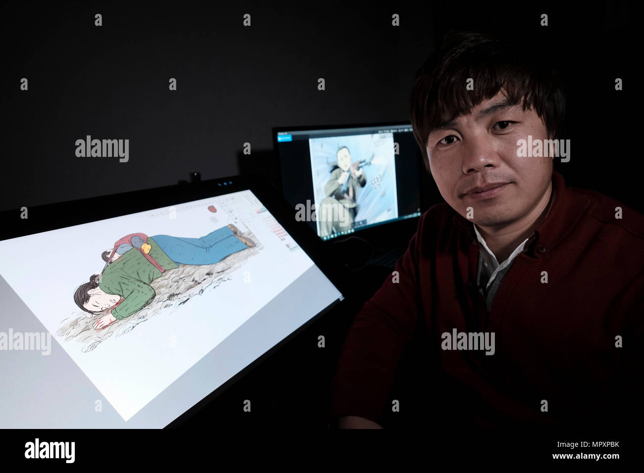 North Korean defector Choi Sung-Guk posing next to a drawing on a computer  depicting a scene from life in North Korea at his home in the city of  Gwangmyeong in Gyeonggi Province