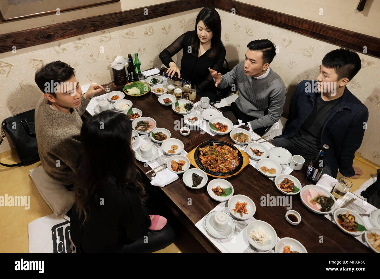 Young Korean people sitting in a restaurant serving traditional Korean