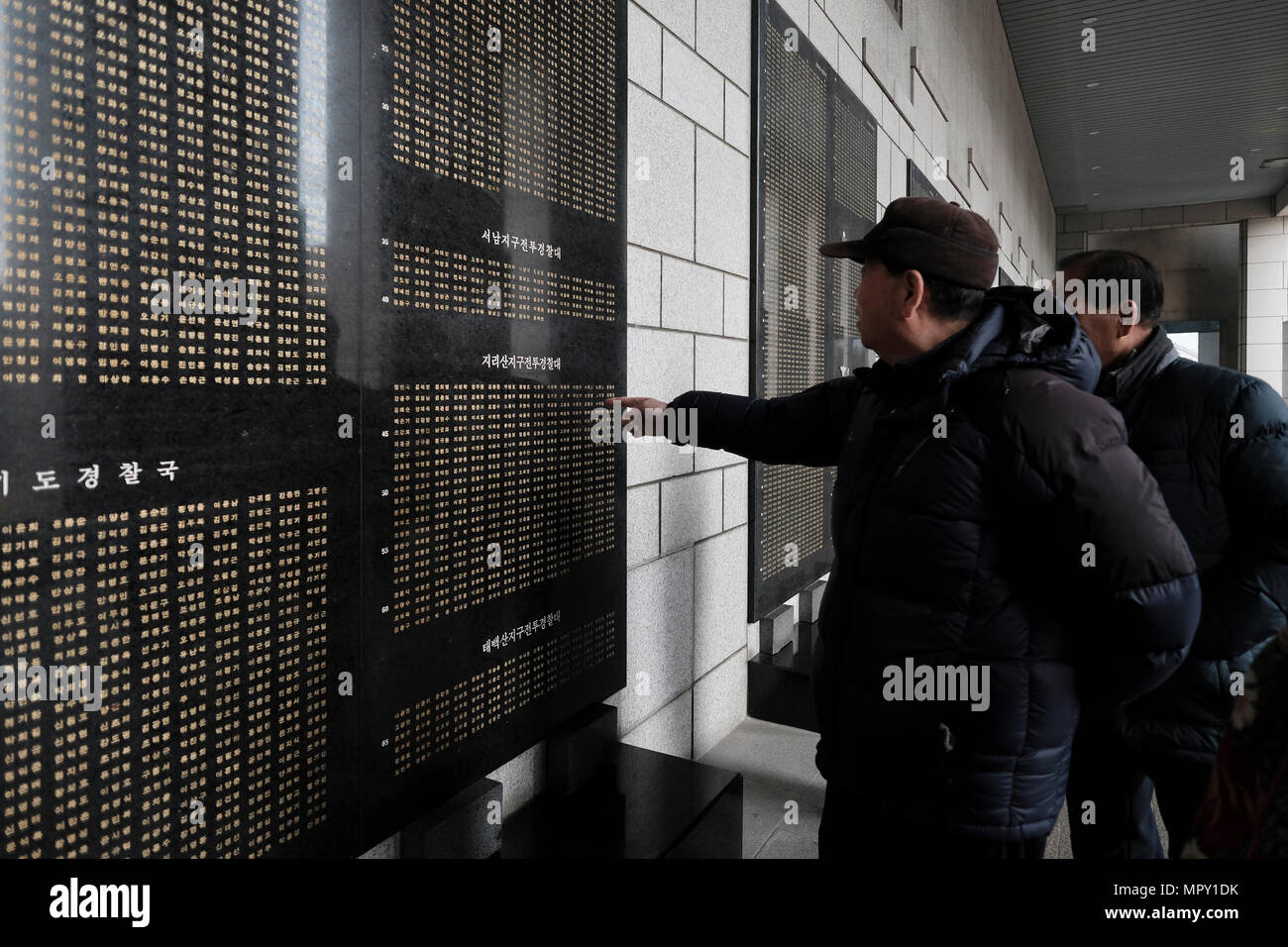 Korean visitors standing in front of a marble panel with names of soldiers killed during the Korean War at the remembrance hall at the War Memorial of Korea museum located in Yongsan-gu district in the city of Seoul capital of South Korea Stock Photo