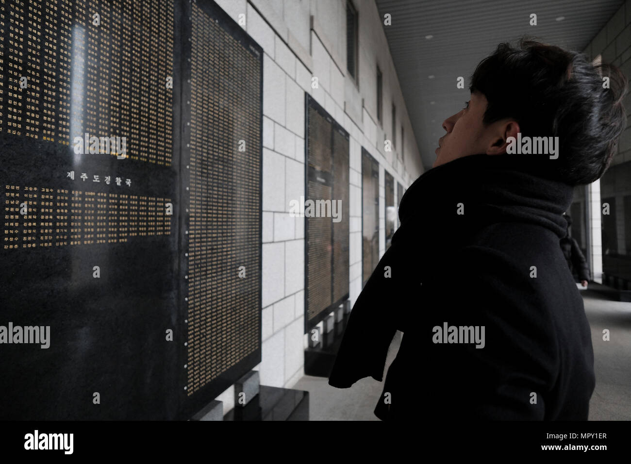 Korean visitor standing in front of a marble panel with names of soldiers killed during the Korean War at the remembrance hall at the War Memorial of Korea museum located in Yongsan-gu district in the city of Seoul capital of South Korea Stock Photo