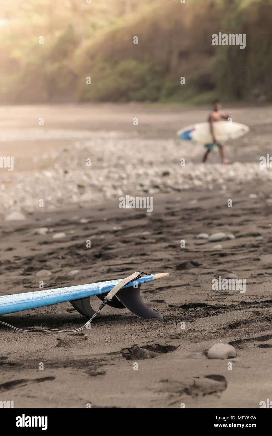 Distant view of man with surfboard walking at beach Stock Photo - Alamy