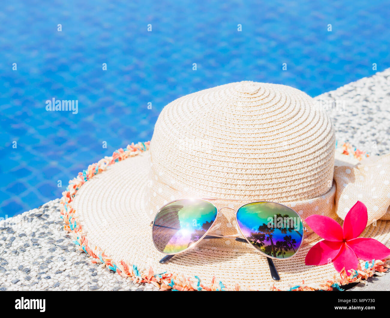 Beautiful summer hat and sunglasses at the side of swimming pool ...