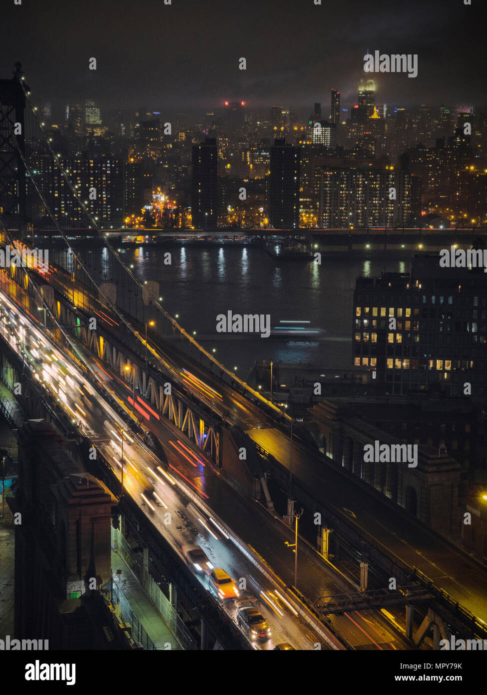 Light trails on bridge over river in illuminated city at night Stock ...