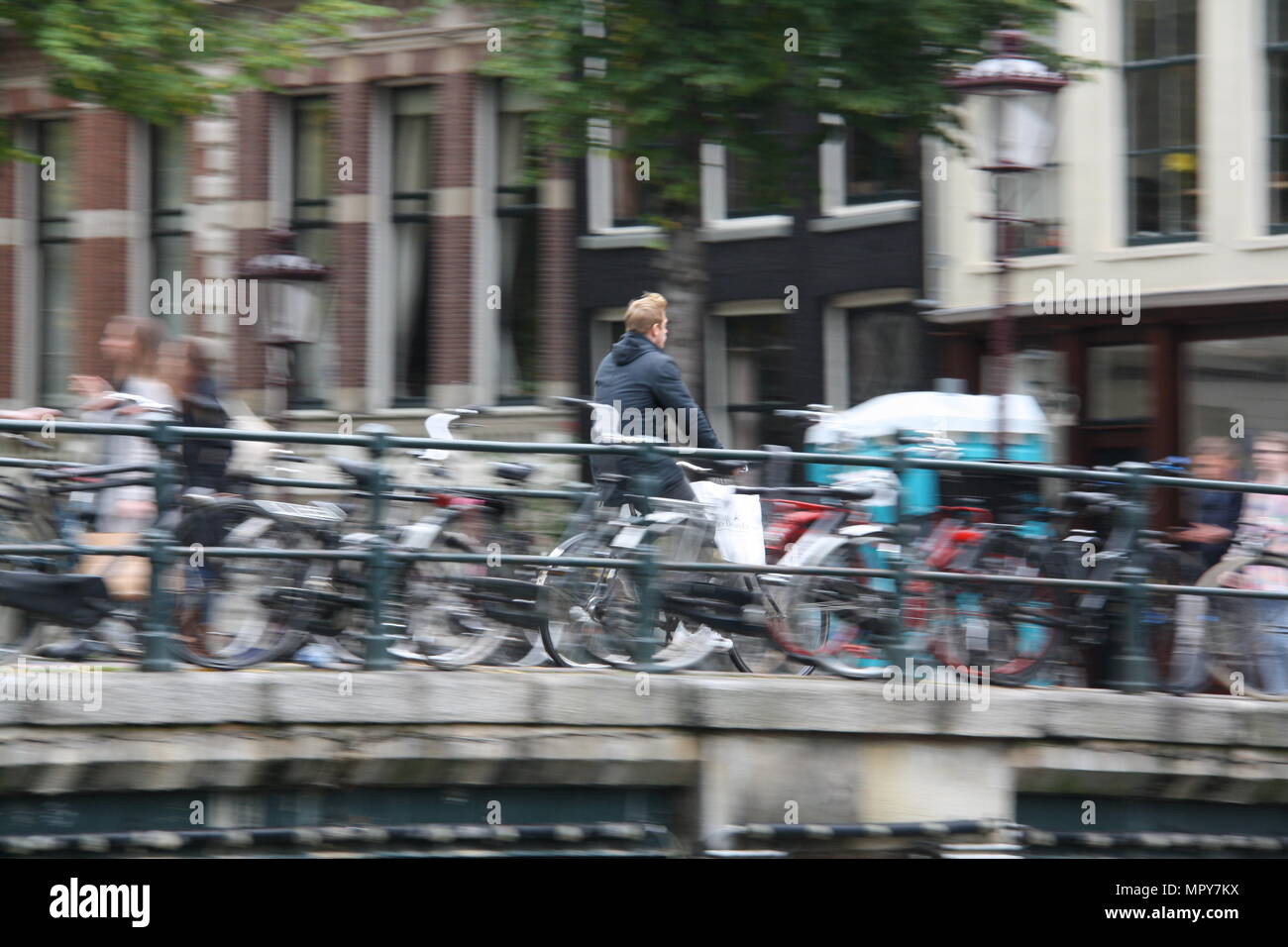 A man rides his bicycle across a canal in Amsterdam, the Netherlands. Stock Photo