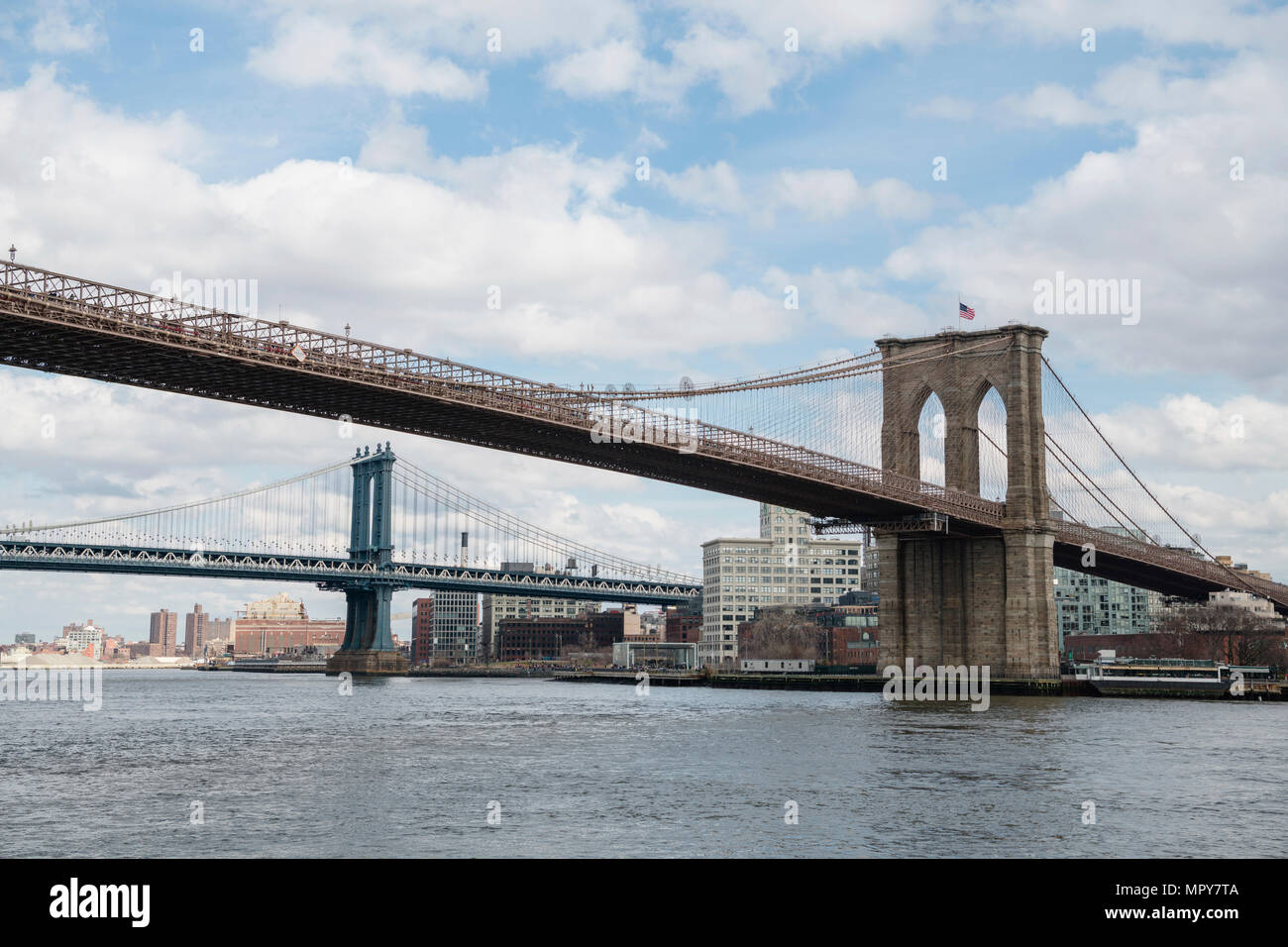 Bridges over East river against cloudy sky in city Stock Photo