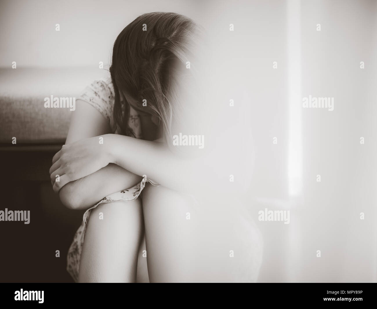 Closeup despaired woman hug her knee and cry while sitting alone on the ...