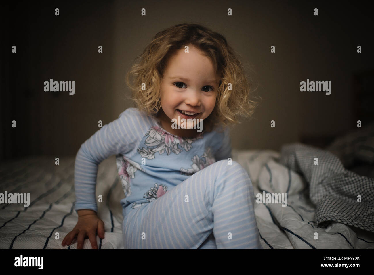 Portrait of smiling girl sitting on bed at home Stock Photo - Alamy