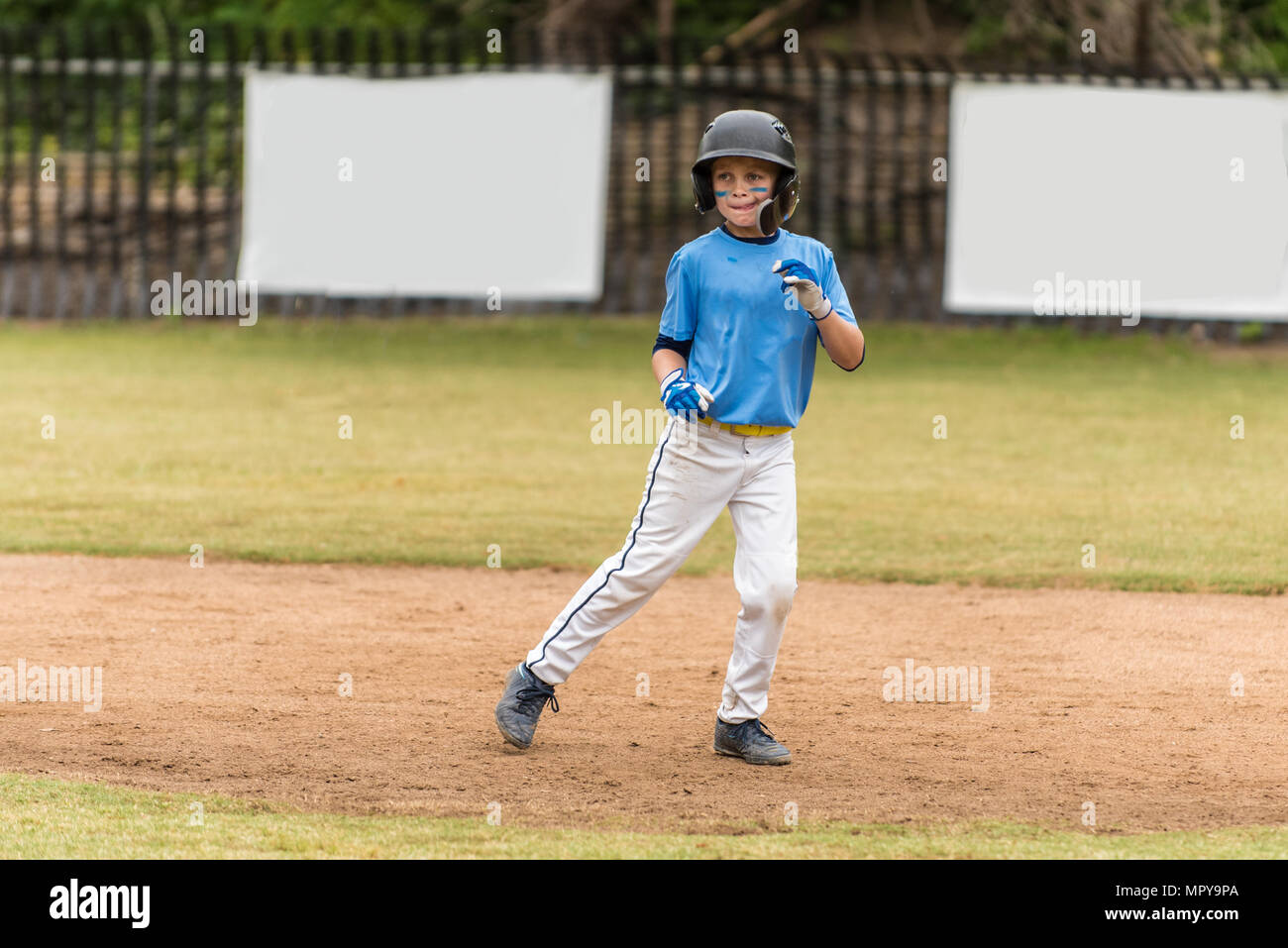 Little league baseball all star in blue uniform leading off on the