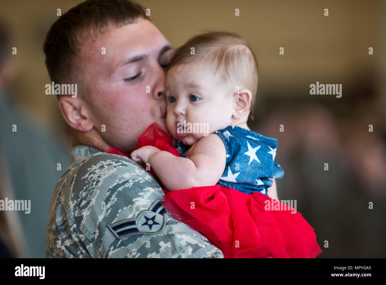 Airman 1st Class Carl Runkel, a munitions crew member with the 3rd Maintenance Group hugs his three-month-old daughter Korra Storm after seeing her for the first time at Hangar 25 on Joint Base Elmendorf-Richardson, Alaska April 21 upon returning from a 7-month deployment. For many families, this was their first time being separated from their loved ones for an extended period of time. (U.S. Air Force photo by Senior Airman Kyle Johnson) Stock Photo