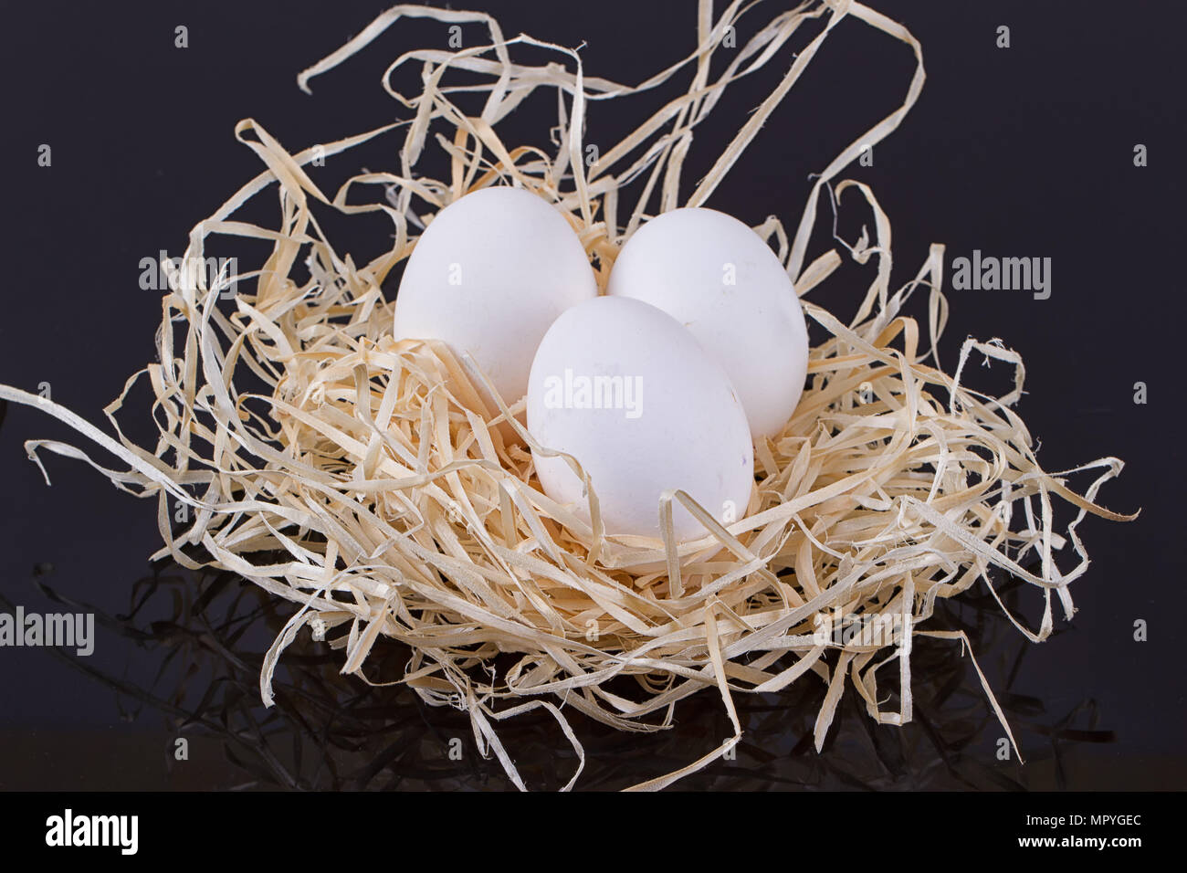 Three chicken eggs in the nest like On a black background Stock Photo ...