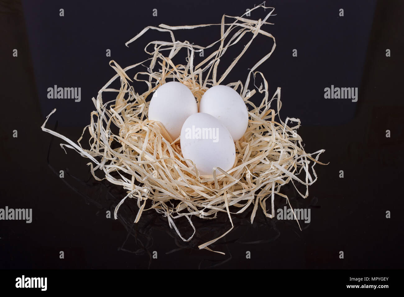 Three chicken eggs in the nest like On a black background Stock Photo ...