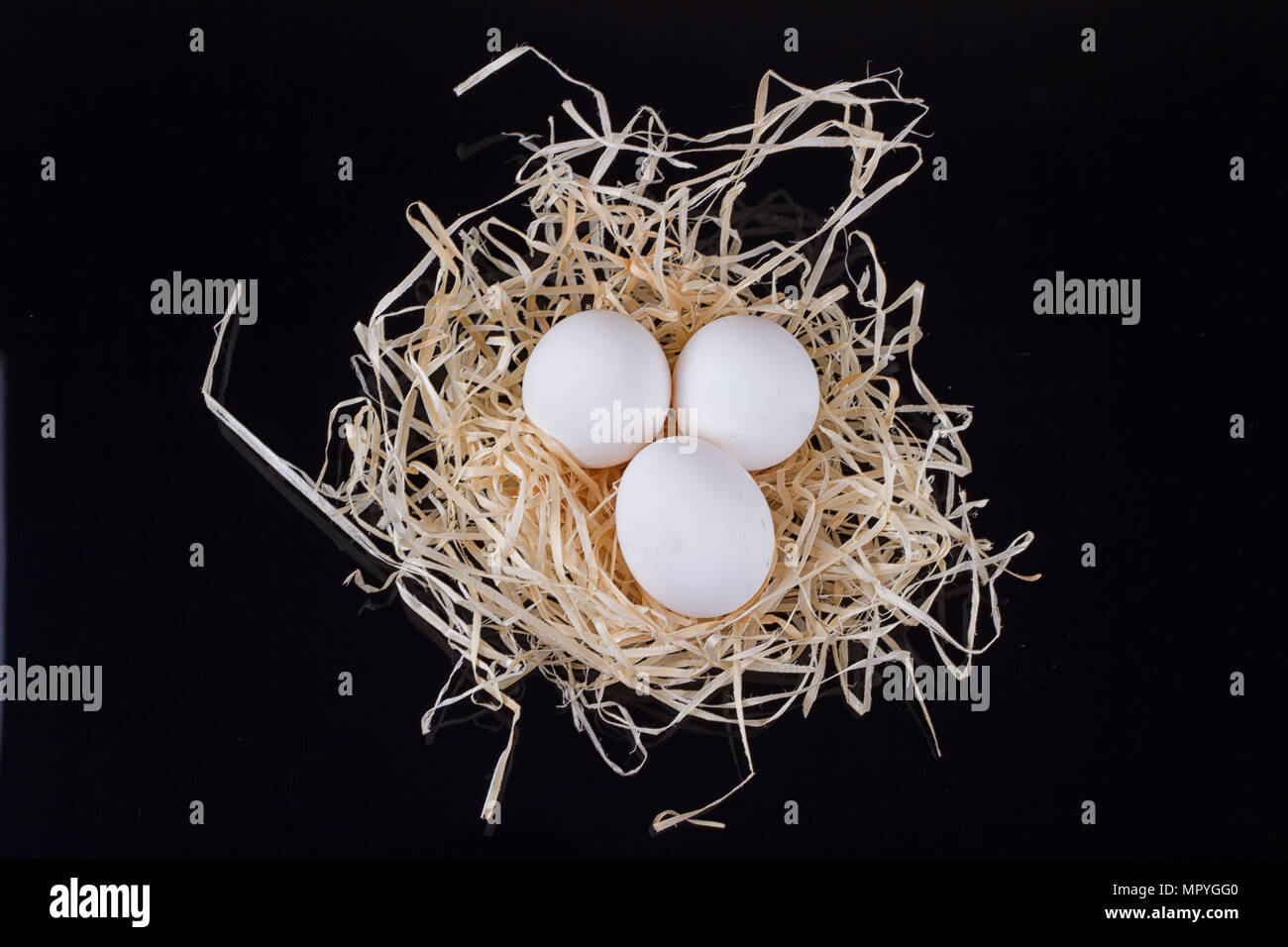 Three chicken eggs in the nest like On a black background Stock Photo ...