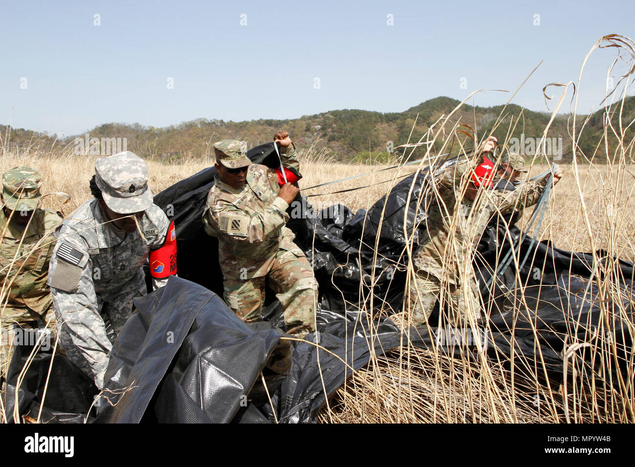 Soldiers from 25th Transportation Battalion work to recover the parachute from a low cost aerial delivery system, April 12, 2017, at a drop zone between Daegu and Busan, South Korea. Multiple U.S. assets and ROK Air Force validated their aerial logistics capabilities as part of ongoing exercise Operation Pacific Reach ’17. Stock Photo