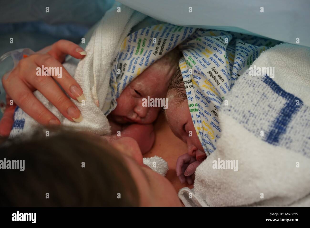 Newborn twins getting skin to skin contact with mother in NHS hospital Stock Photo