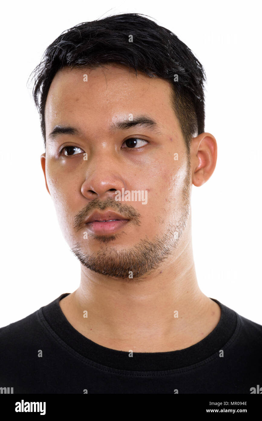 Face of young Asian man thinking while looking at distance Stock Photo