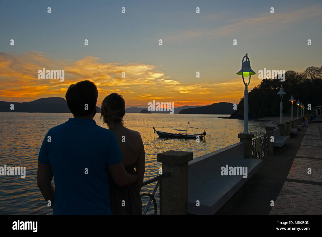 Couple viewing setting sun Cape Panwa viewpoint Phuket Thailand Stock Photo