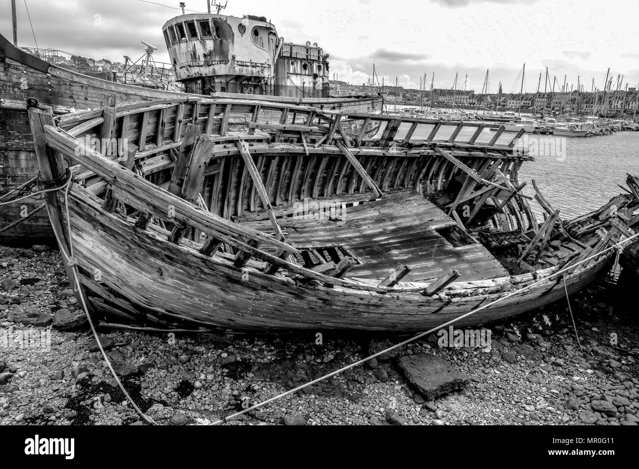 Crumbling ships in the boat graveyard at Camaret-sur-Mer in the Finistere region of Brittany, France. Black and white. B&W Stock Photo