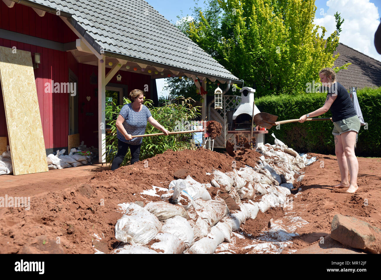 25 May 2018, Germany, Trassem: Homeowners Pascale Fuelling (l) and Carole Henkgen clearing up on the terrace. Heavy rain caused a landslide in Trassem in western Germany, which damaged several properties. Photo: Harald Tittel/dpa Stock Photo