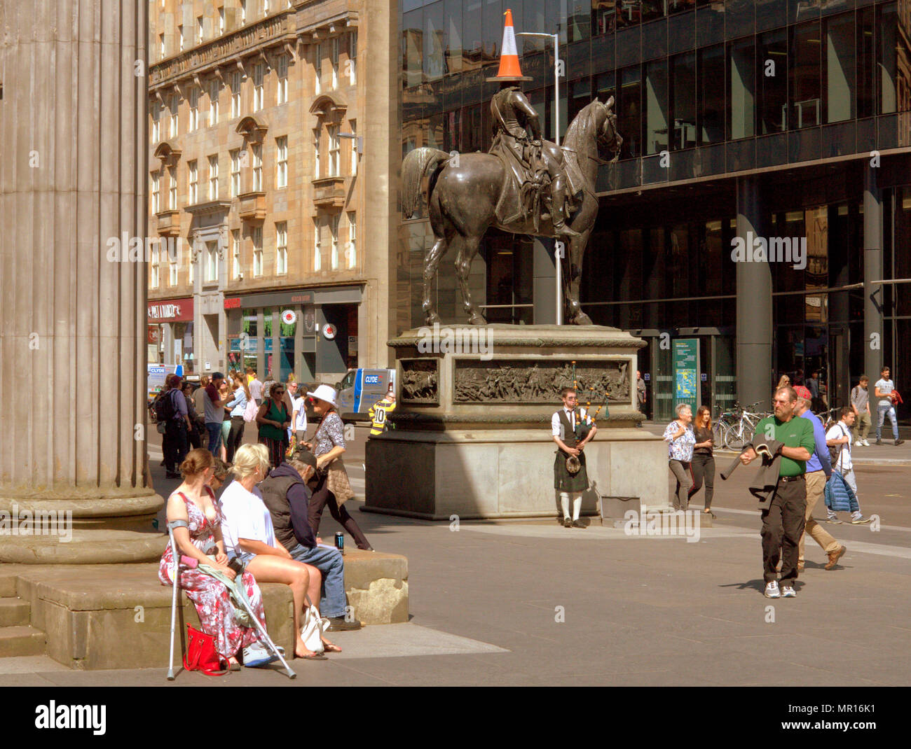 Glasgow, Scotland, UK 25thMay.UK Weather: Sunny Summer weather cooks the city on its warmest day as the centre lets tourists and locals enjoy the sun. The cone head man outside gallery of modern art goma  museum is always a tourist hot spot especially with a lone piper, an unsual sight. Gerard Ferry/Alamy news Stock Photo