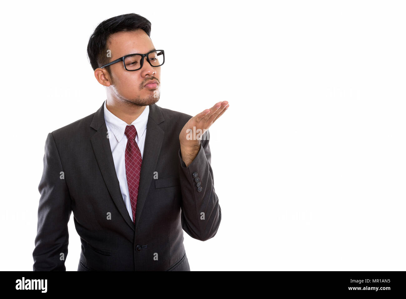 Studio shot of young Asian businessman giving flying kiss Stock Photo
